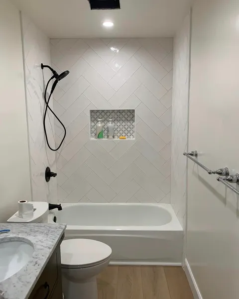 Remodeled bathroom with white herringbone shower tile, a mosaic niche, and matte black fixtures