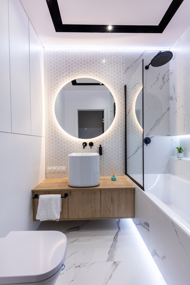 Small modern bathroom with a backlit round mirror and floating wood vanity