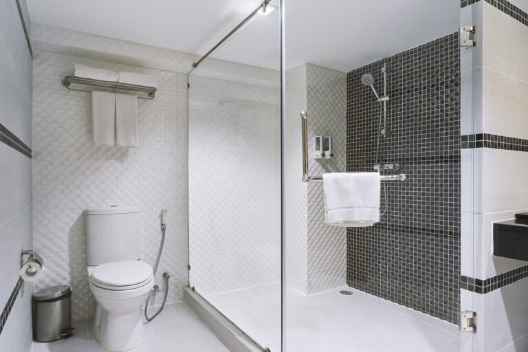 Walk-in glass shower with black mosaic tile