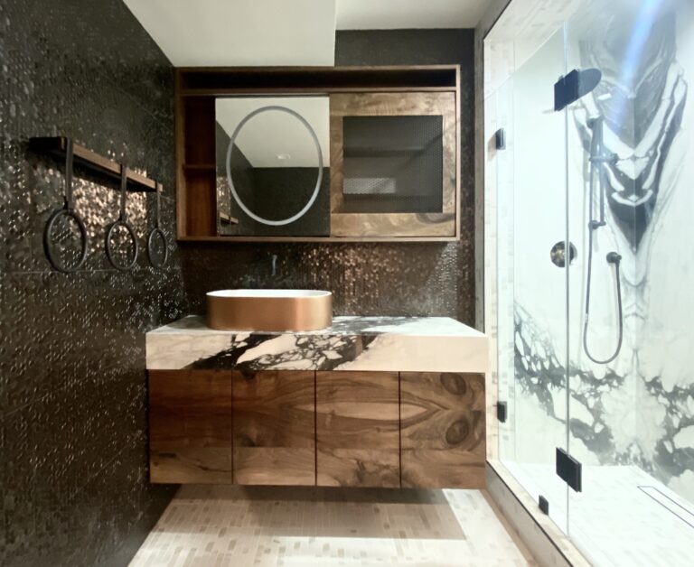 Frameless glass shower beside a vanity and mirror