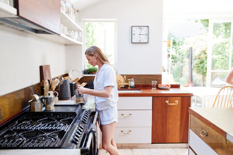 Homeowner making coffee in a kitchen with open shelving
