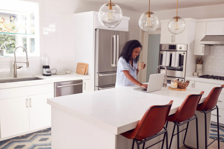 Homeowner working at the island of a bright white kitchen