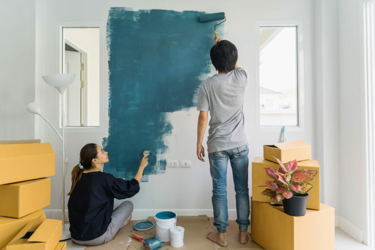 young couple painting an interior wall with paint rollers